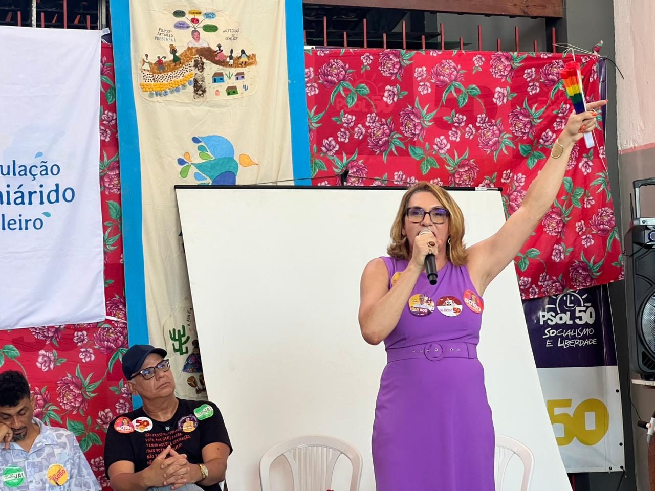 Linda Brasil fala ao microfone durante encontro da Articulação Semiárido Brasileiro, diante de bandeiras da ASA e do PSOL