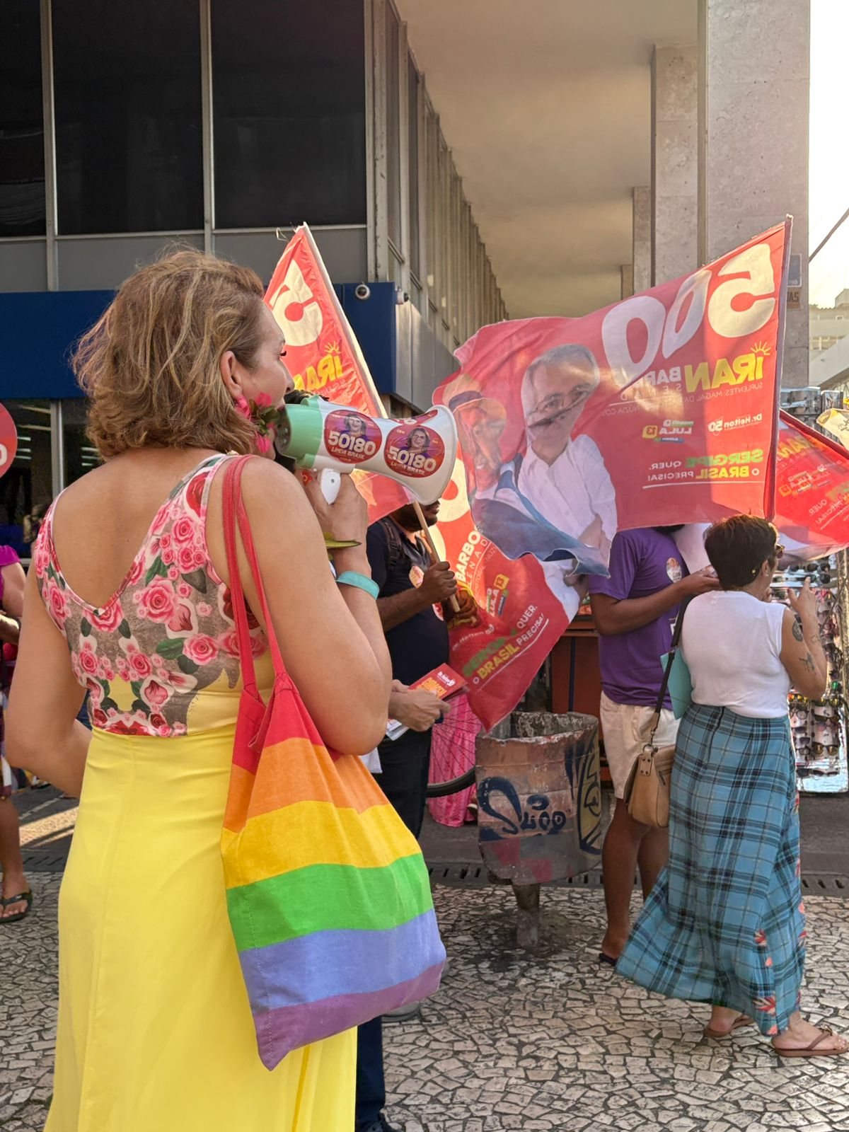 Linda Brasil fala ao megafone diante de bandeiras da campanha no Centro de Aracaju
